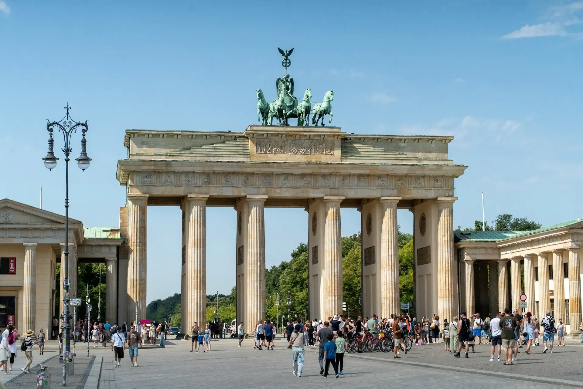 The Brandenburg Gate illuminated at dusk with people crossing Pariser Platz
